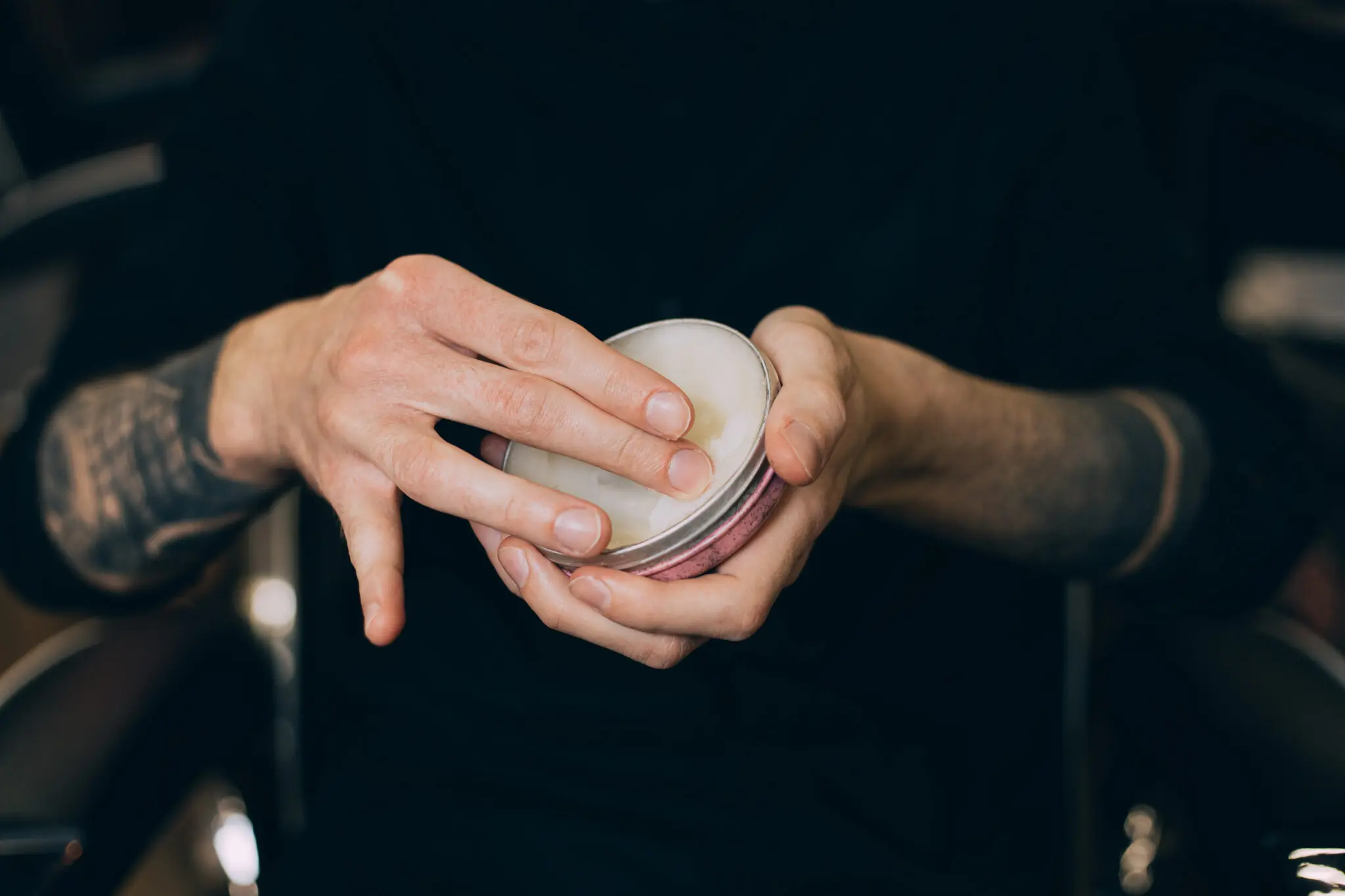 Hand applying pomade from tin container