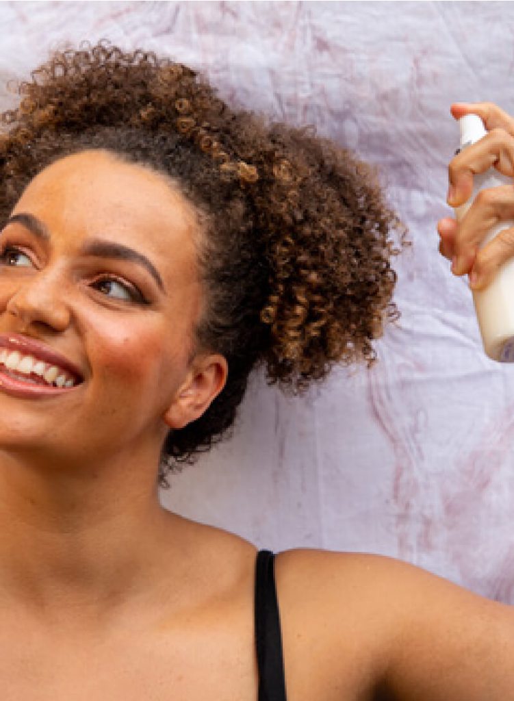 Woman spraying curly hair product outdoors