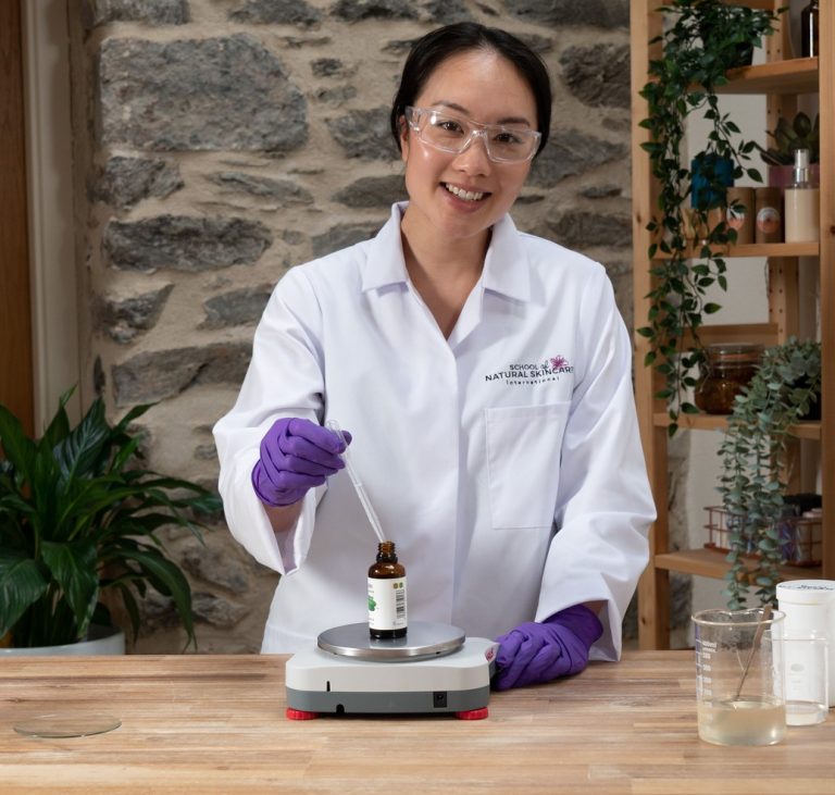 Woman in lab coat using pipette in laboratory.