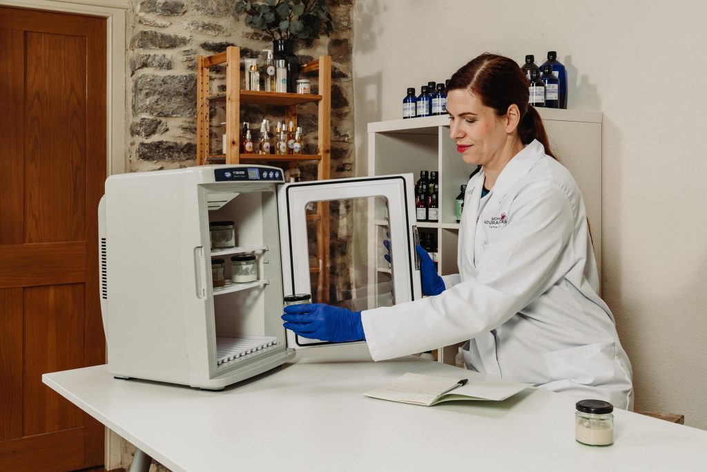 Scientist placing jar in laboratory mini fridge.