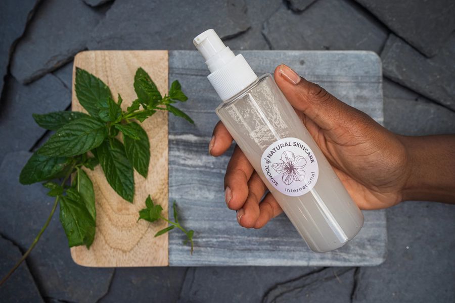 Hand holding natural skincare product with mint leaves