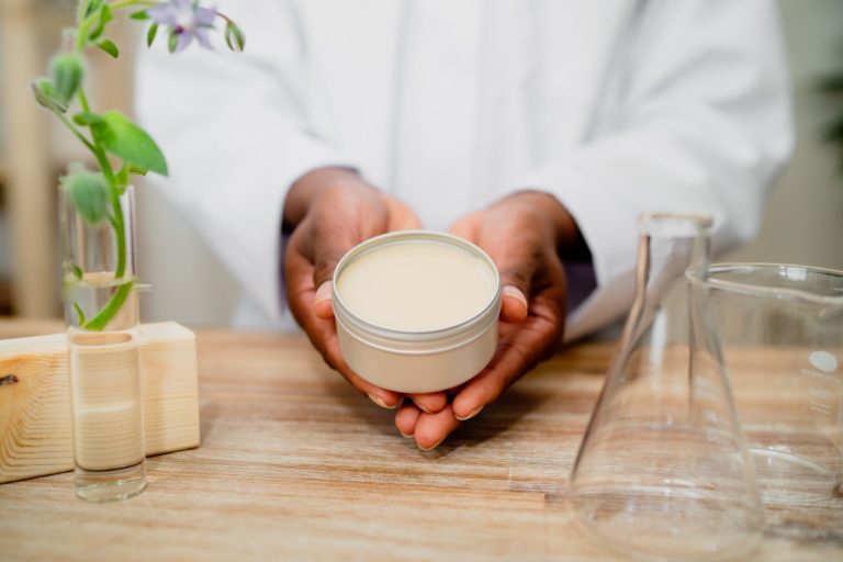 Hands holding jar of cream, plant science setup