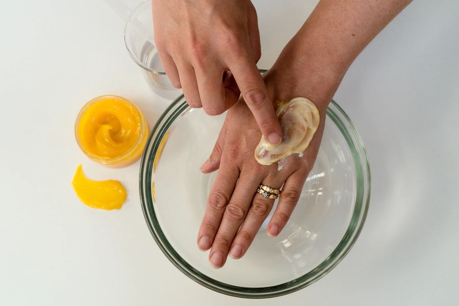 Applying cream to hand in glass bowl