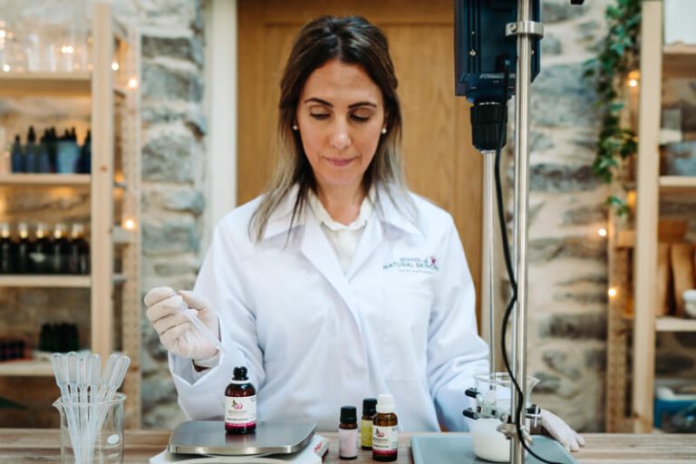 Woman in lab coat working with essential oils.