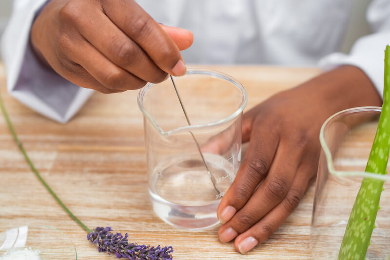 Mixing liquid in beaker with lavender and aloe