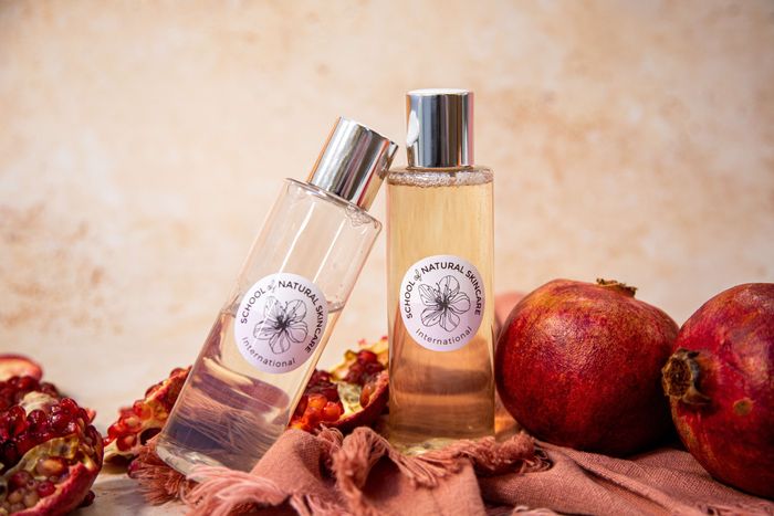 Natural skincare bottles with pomegranates on cloth.