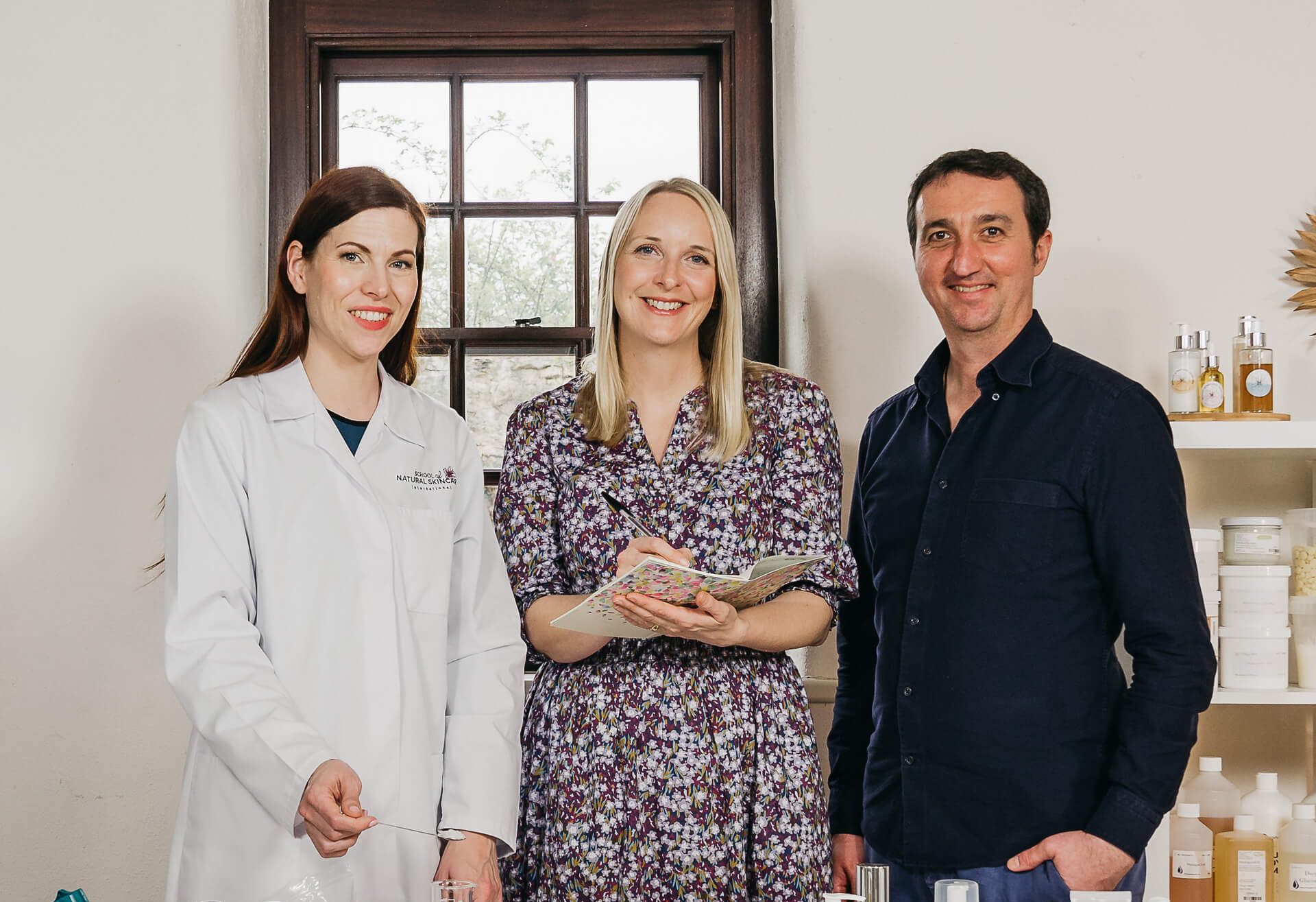 Three people smiling in laboratory setting