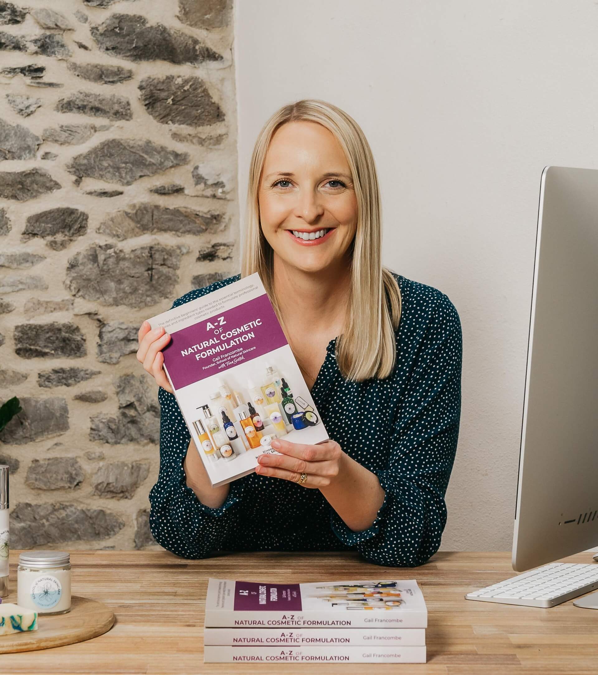 Author holding "A-Z of Natural Cosmetic Formulation" book.