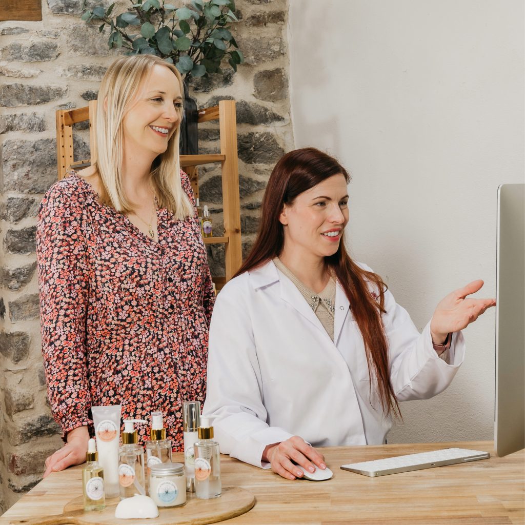 Women discussing skincare products at computer