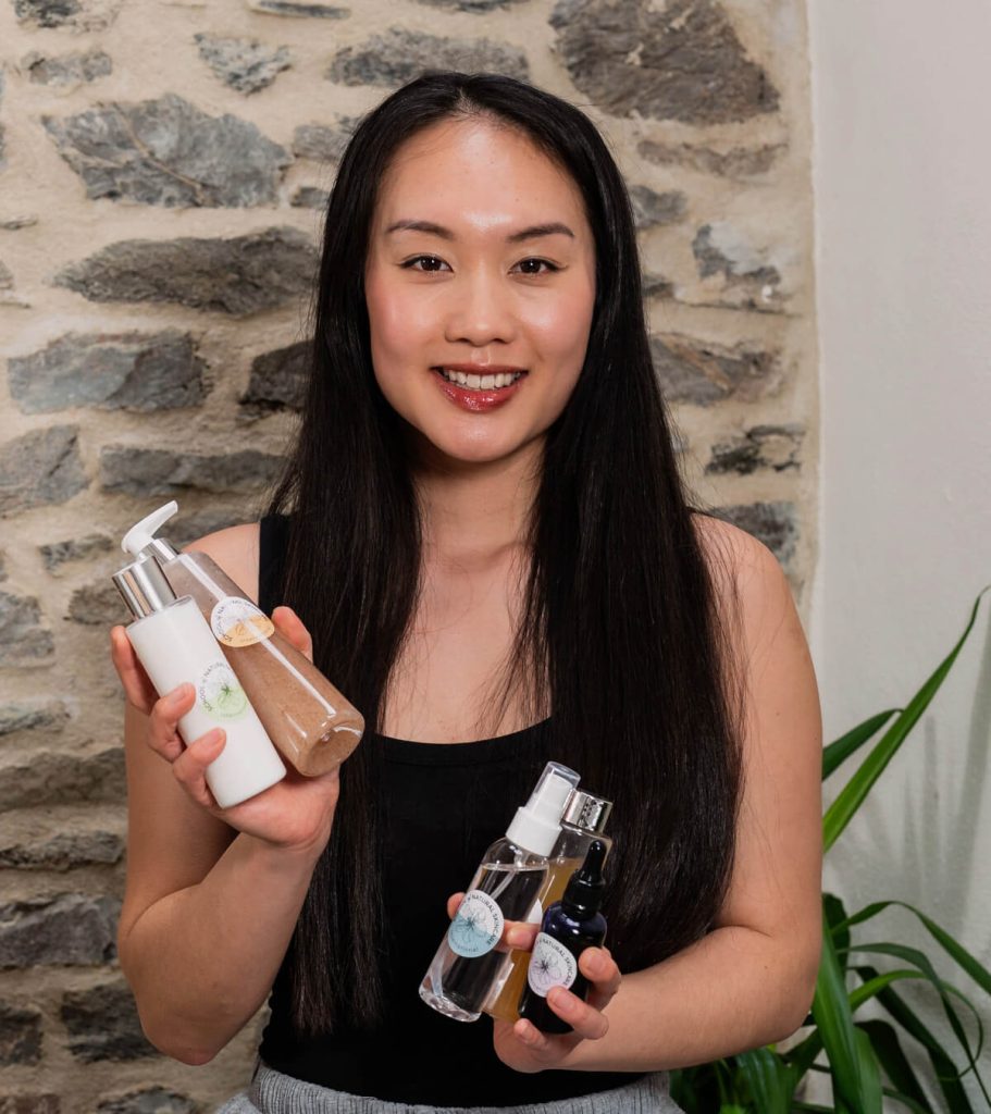 Woman holding various skincare products.