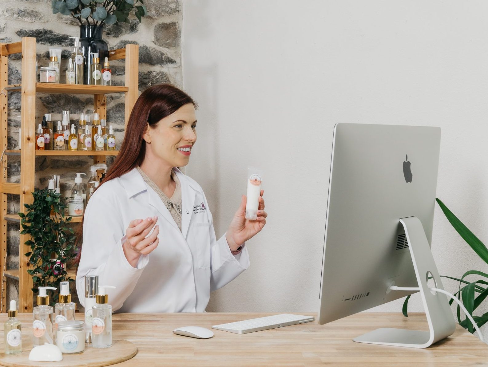 Woman in lab coat showcasing skincare products online.