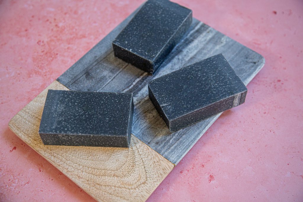 Three black soap bars on wooden board