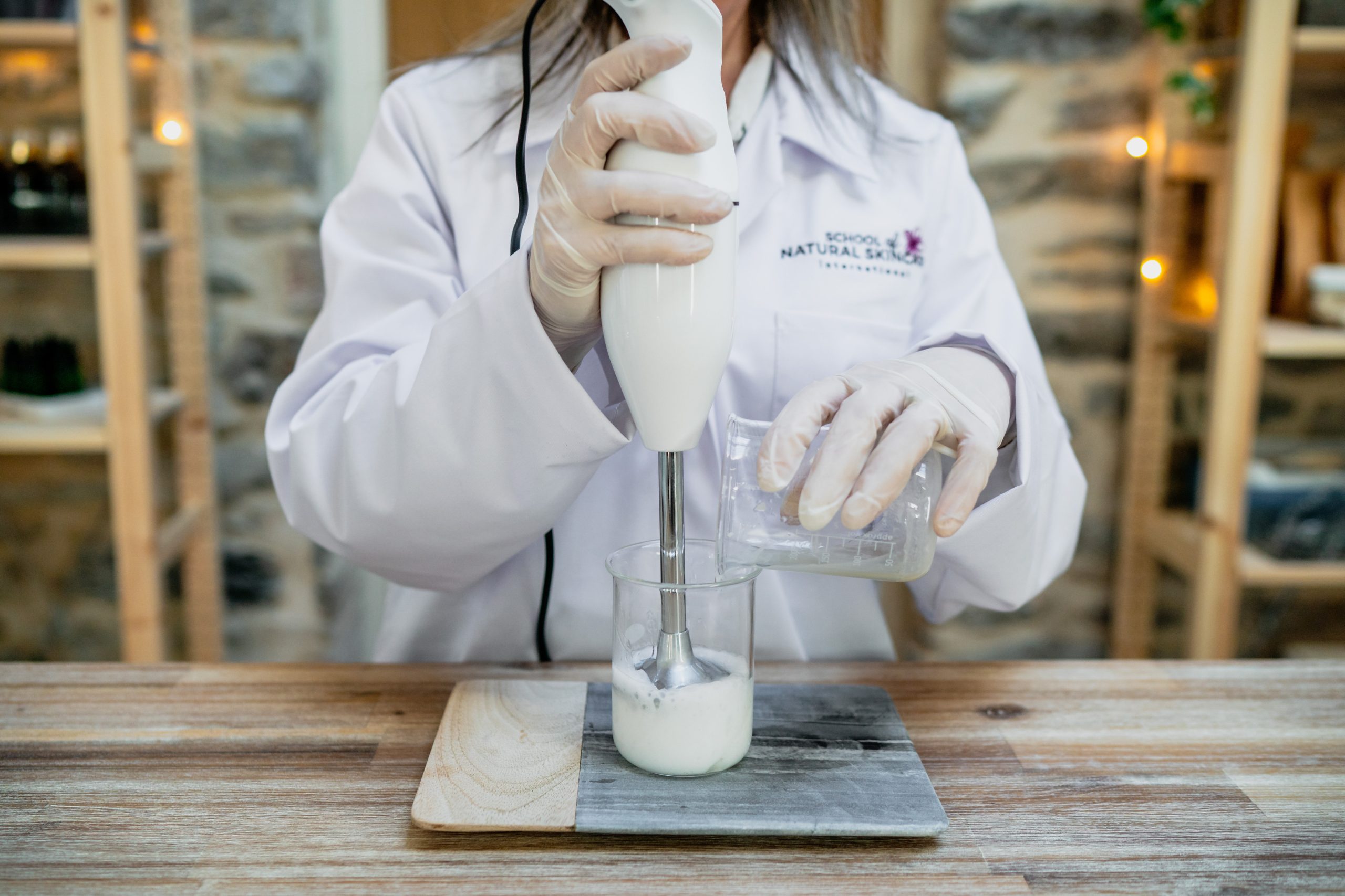 Scientist mixing ingredients in beaker with hand blender.