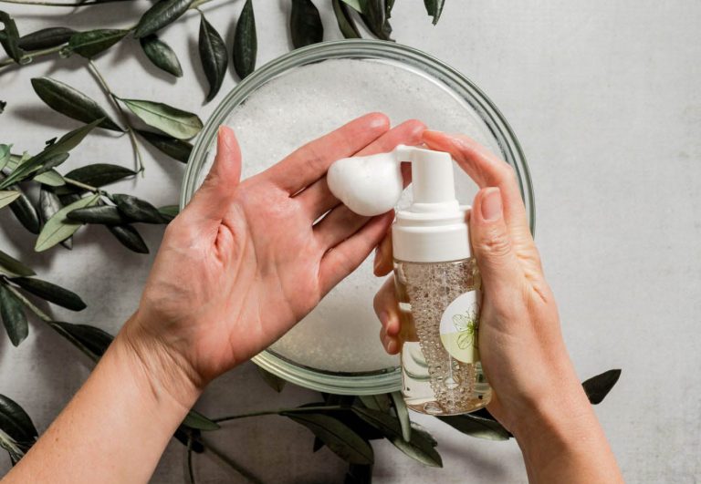 Hands using foaming soap with olive leaves