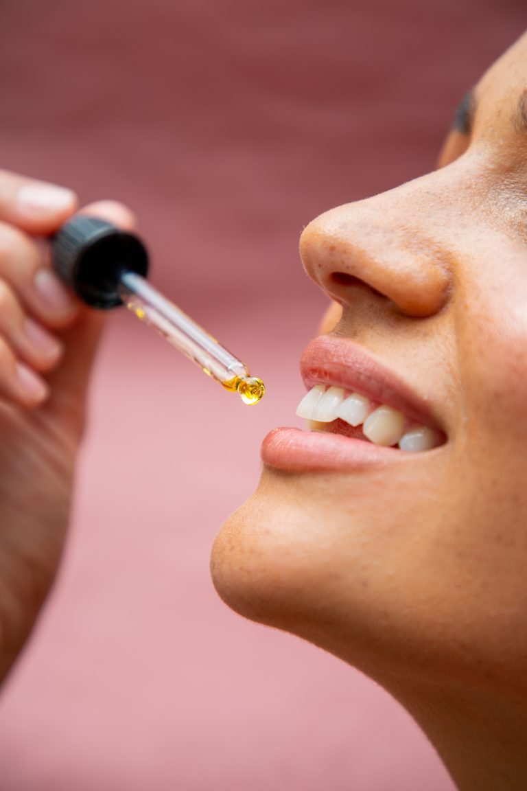 Smiling person applying facial oil with dropper.