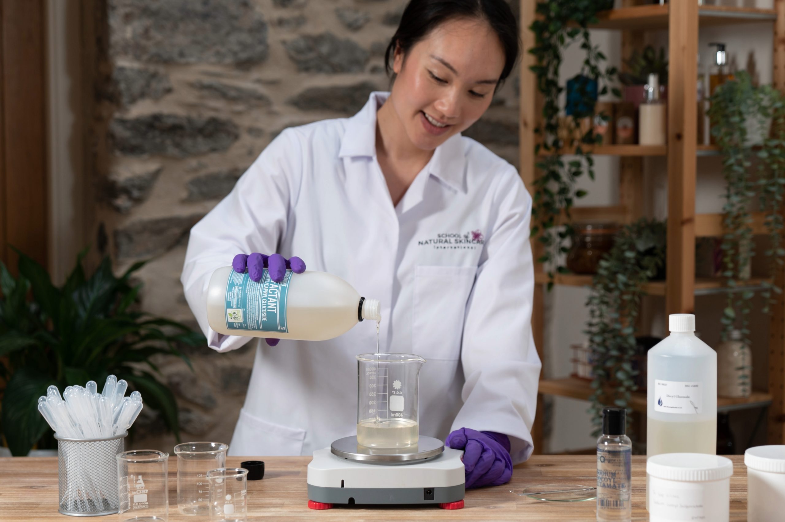 Person pouring liquid into beaker in lab.