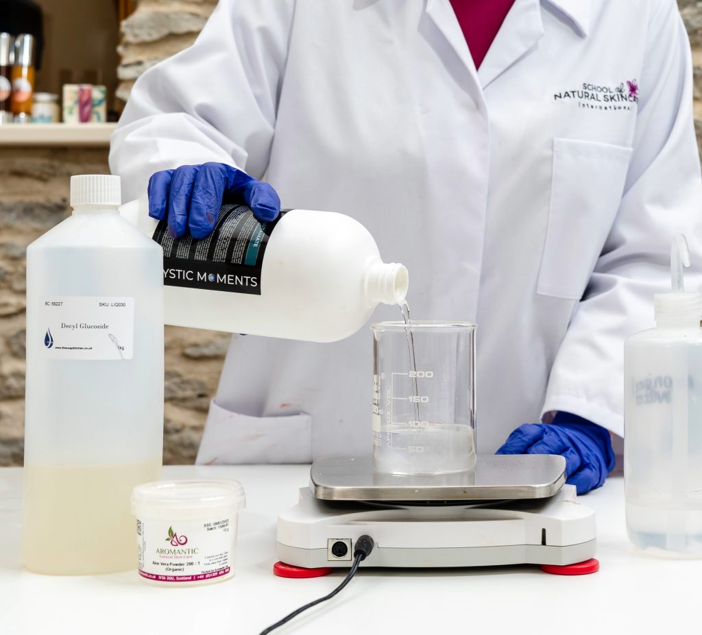 Scientist pouring liquid into a beaker on scale.