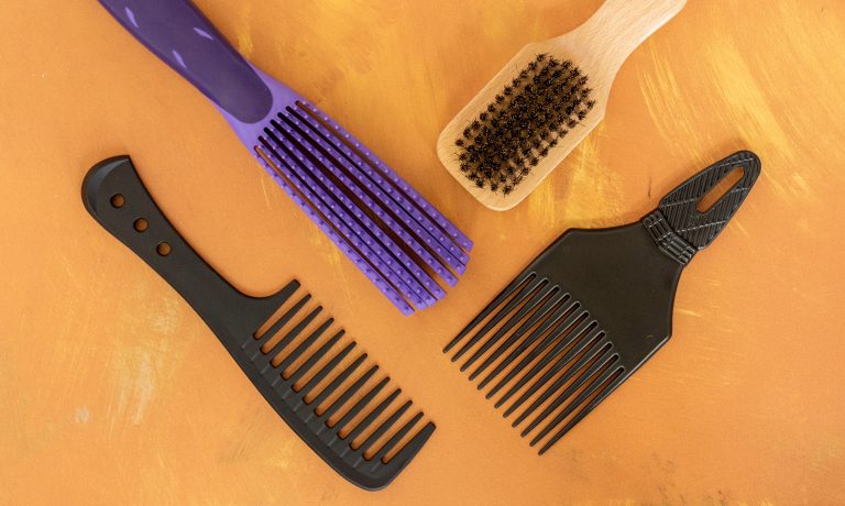 Variety of hairbrushes and combs on orange background.