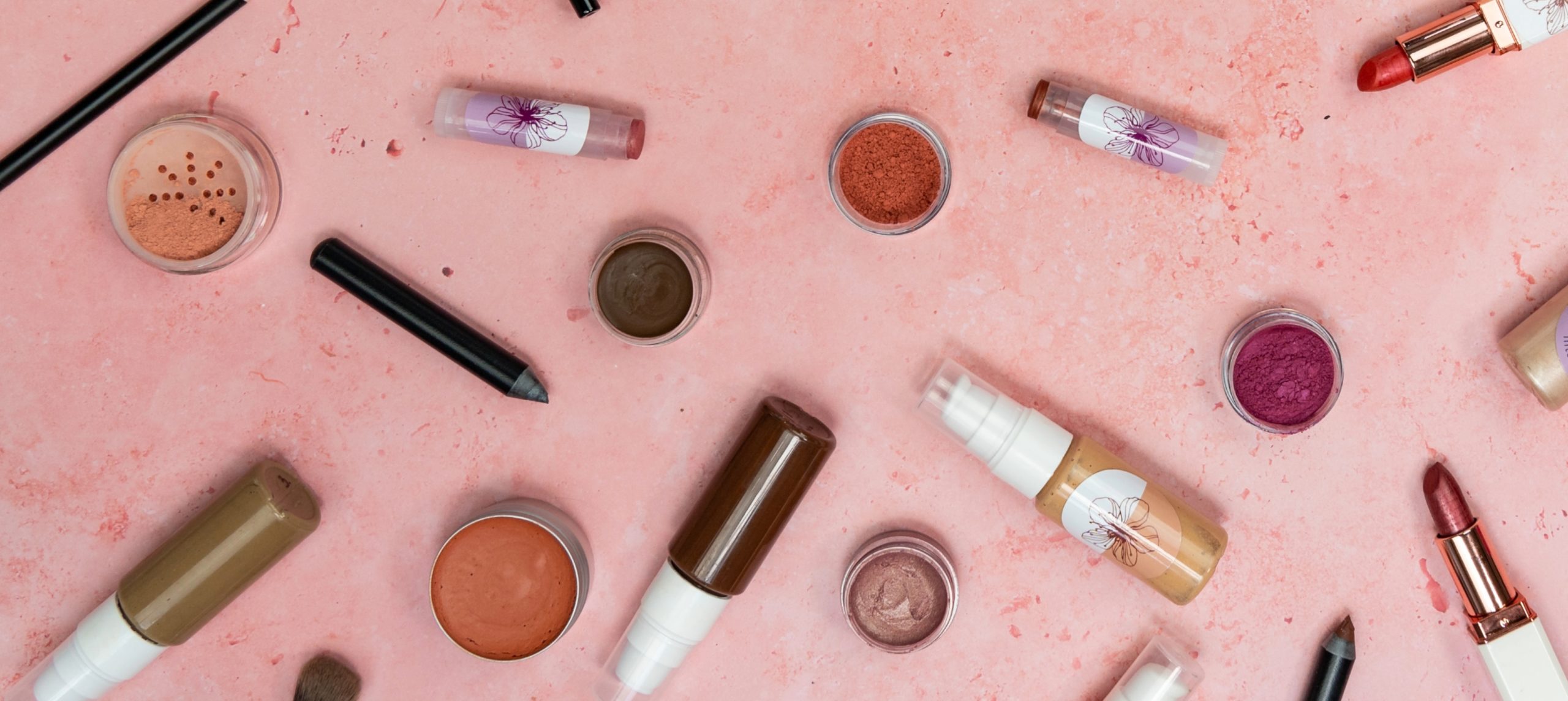 Assorted makeup products on pink background