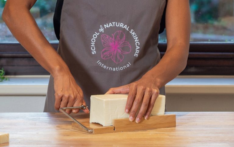 Person slicing block of soap with wire cutter.