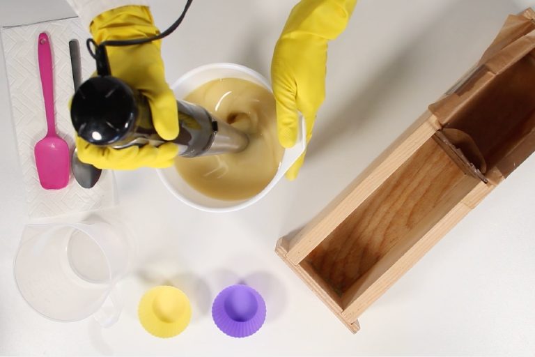 Mixing soap ingredients with immersion blender in bowl.