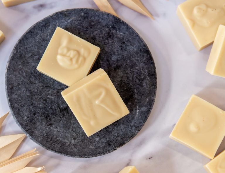 Beige square soap bars on dark round slate.