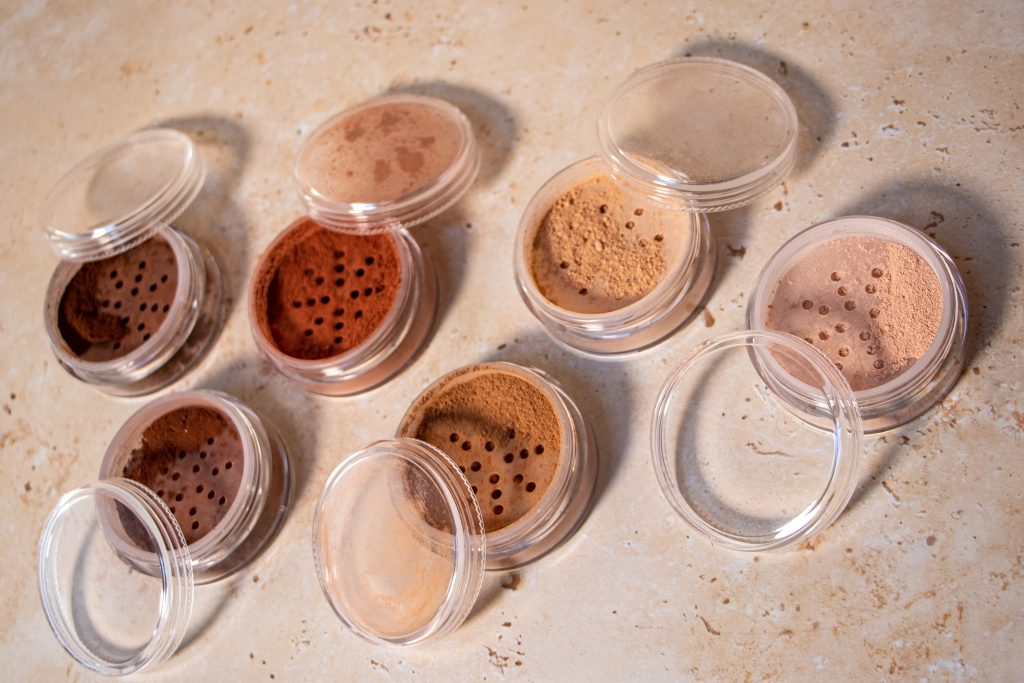 Various shades of loose powder makeup on table.