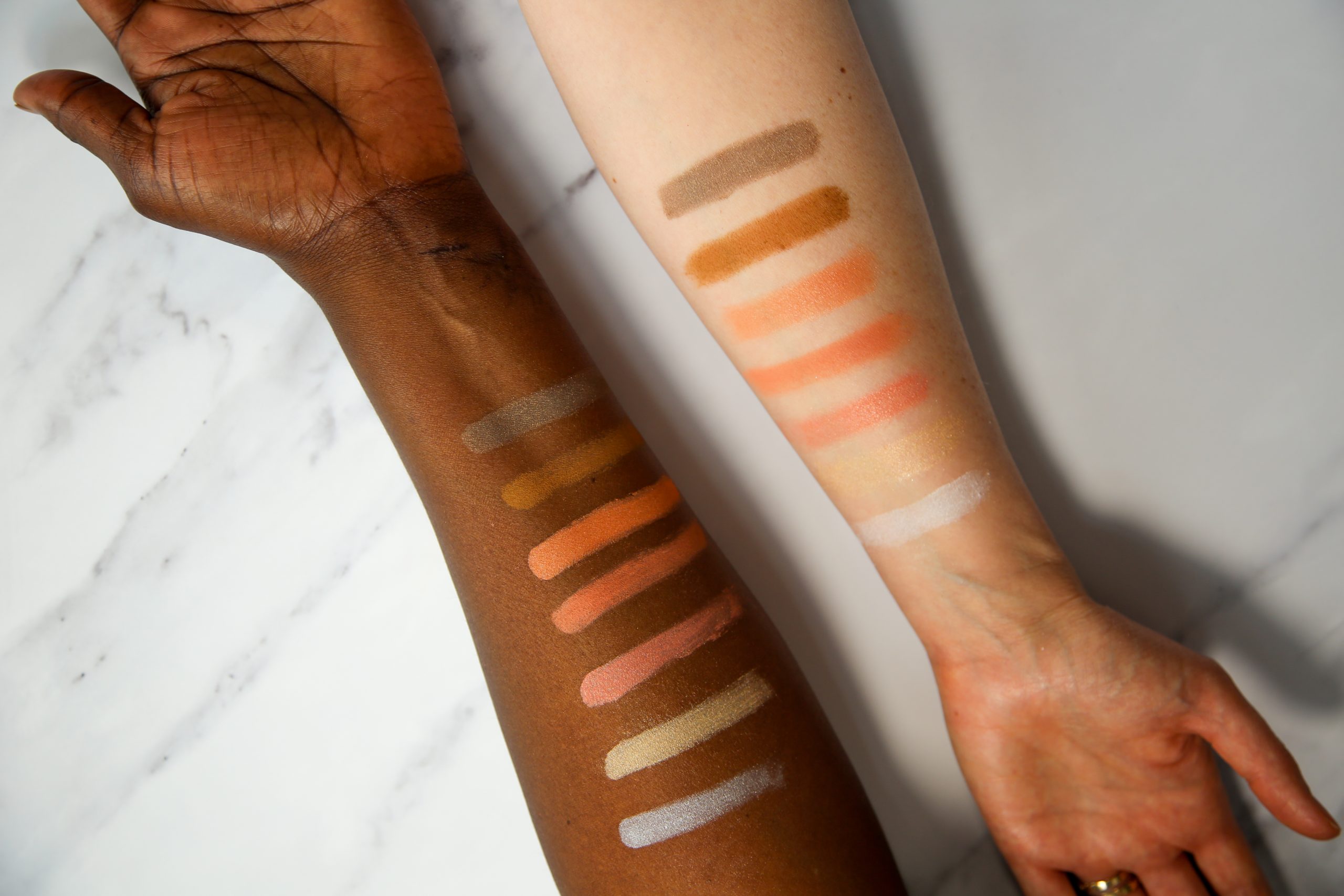 Diverse skin tone makeup swatches on arms.