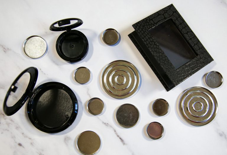 Empty makeup compacts and magnetic pans on table.