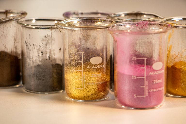 Colorful powders in laboratory beakers on a table.