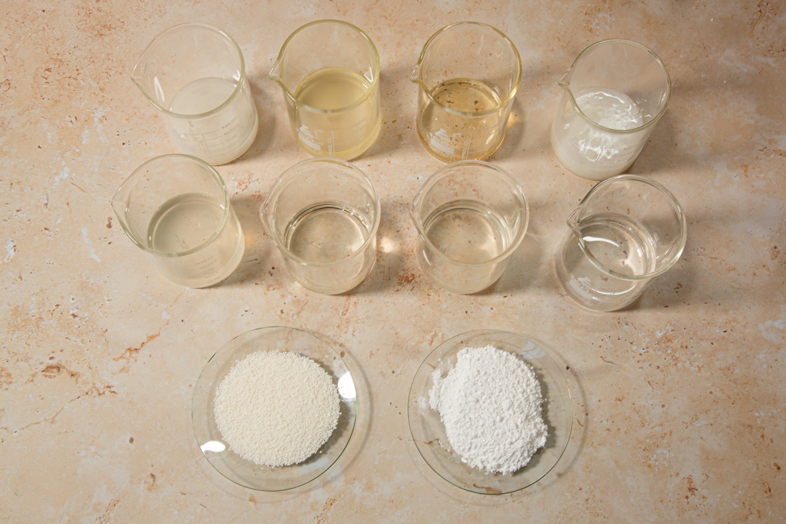 Chemical solutions and powders in containers on table.