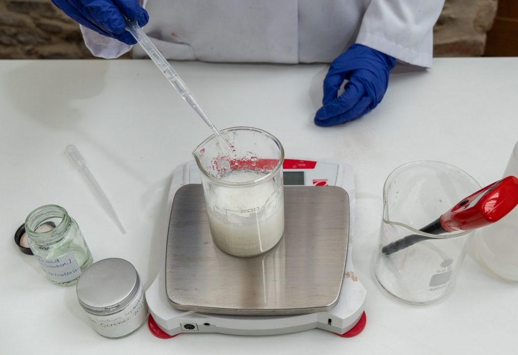 Lab technician preparing chemical solution on scale.