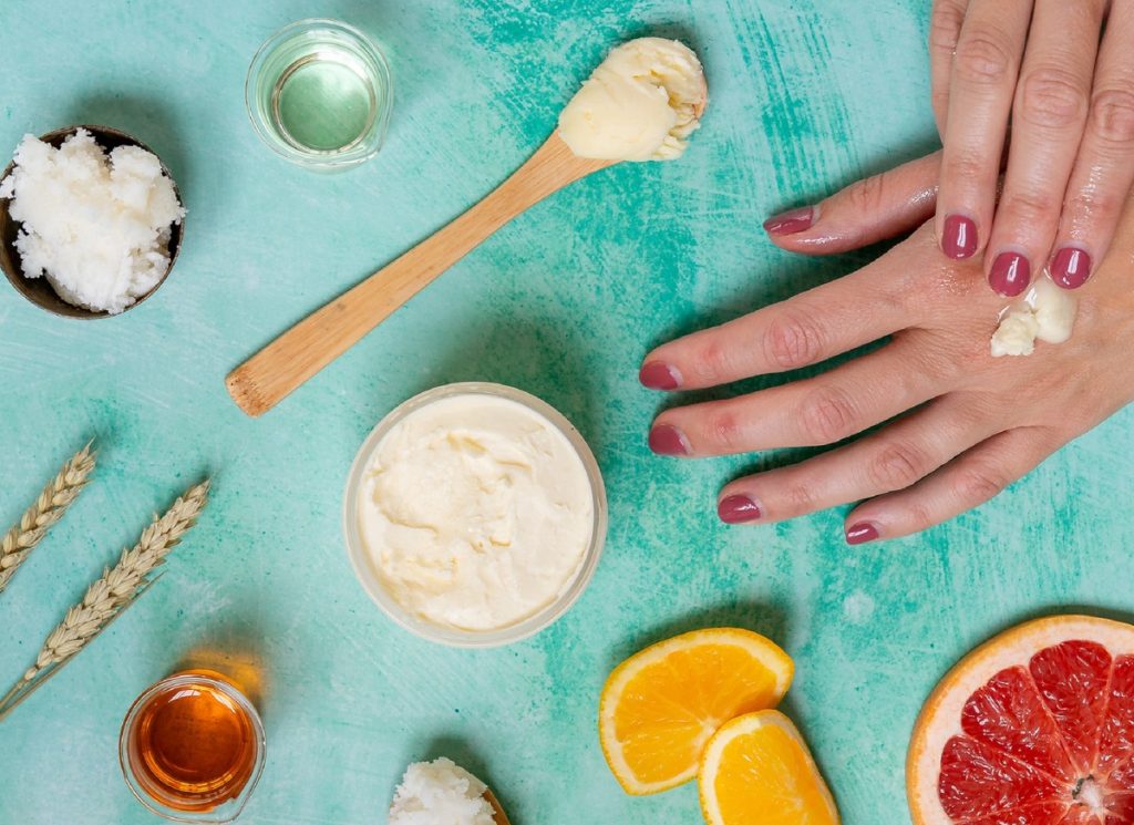 Hand applying natural cream on turquoise background.