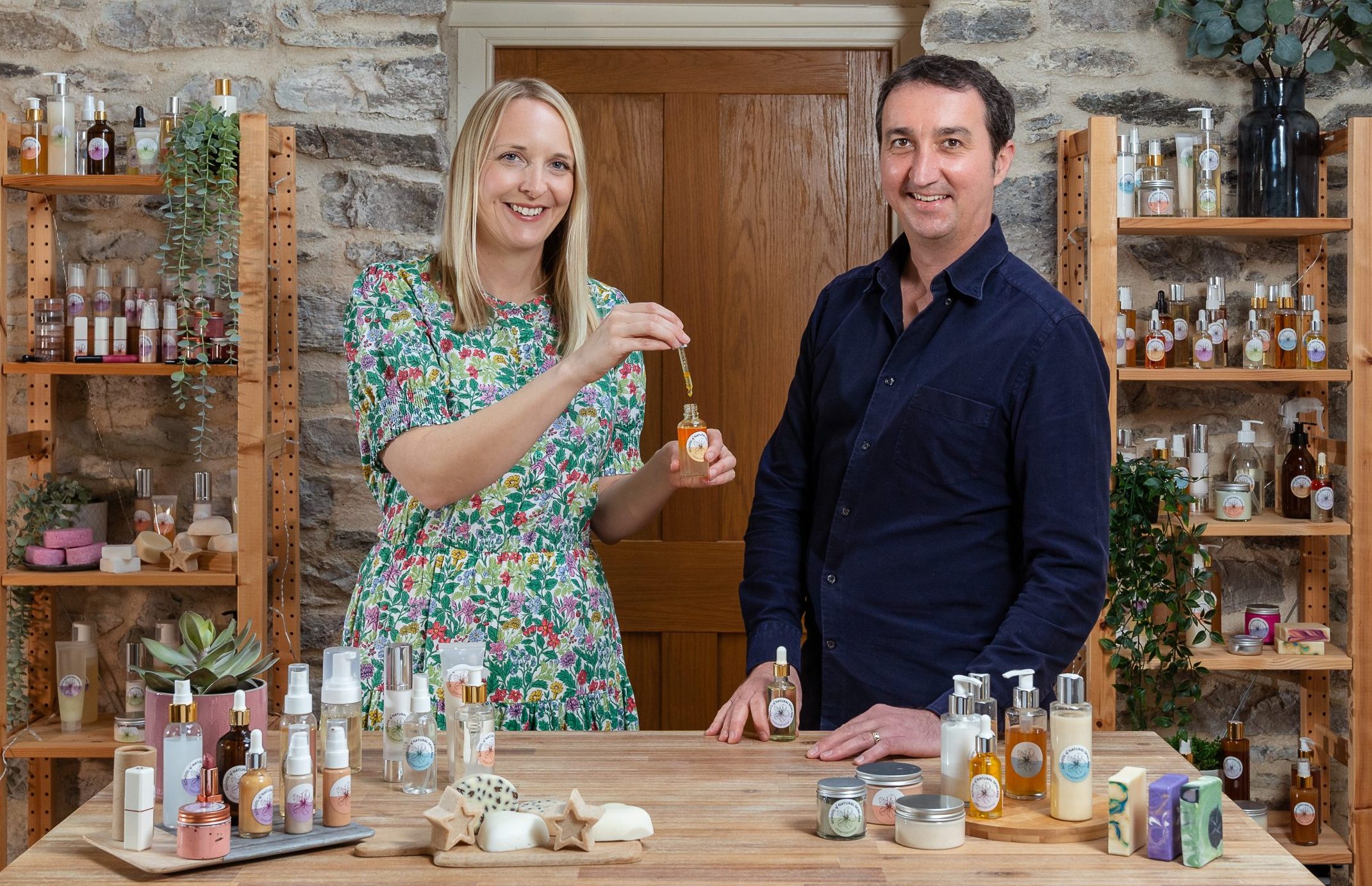 Two people showcasing beauty products on shelves and table.