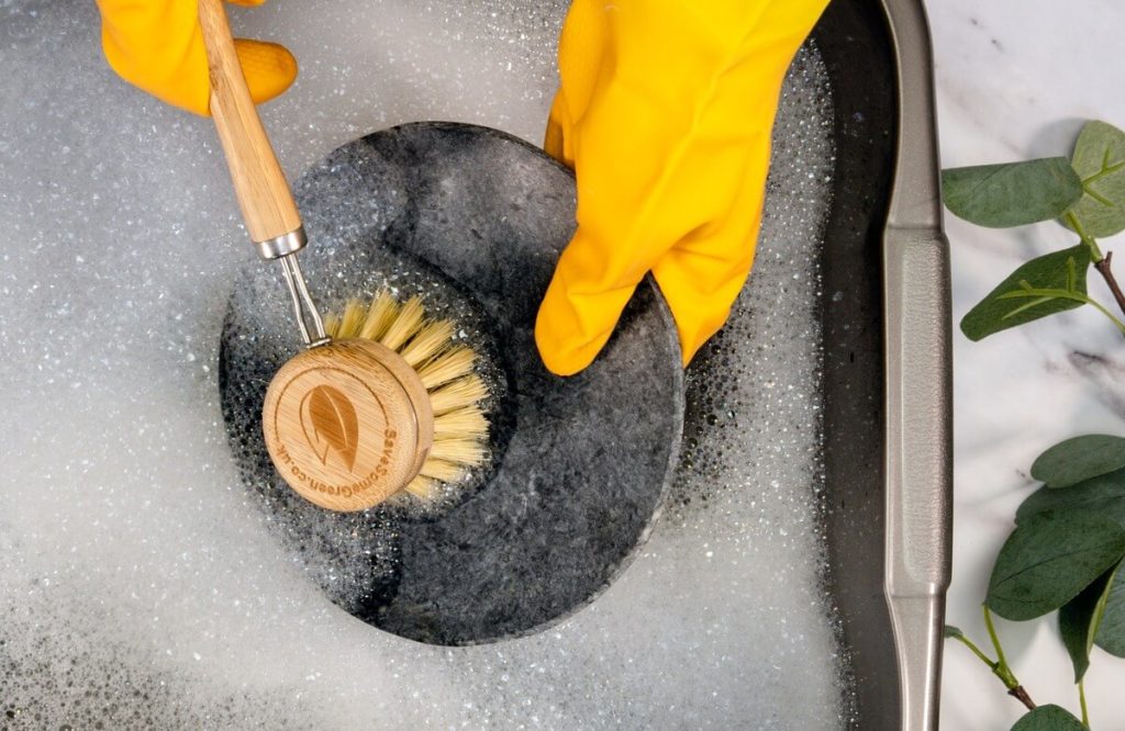 Cleaning a pan with brush and yellow gloves