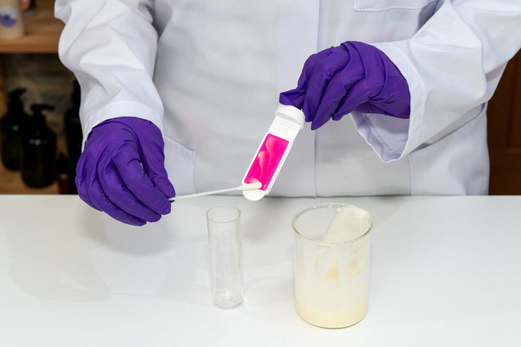 Lab technician testing pink chemical sample.