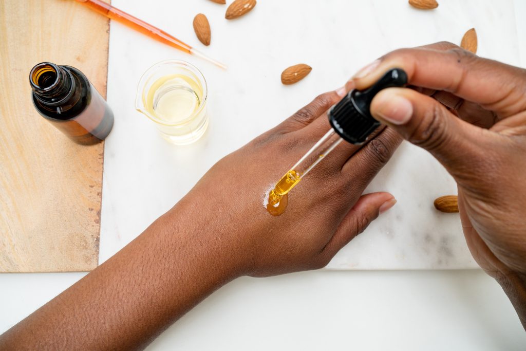 Applying almond oil to hand with dropper