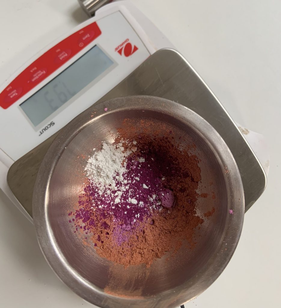 Colorful powders in bowl on digital scale