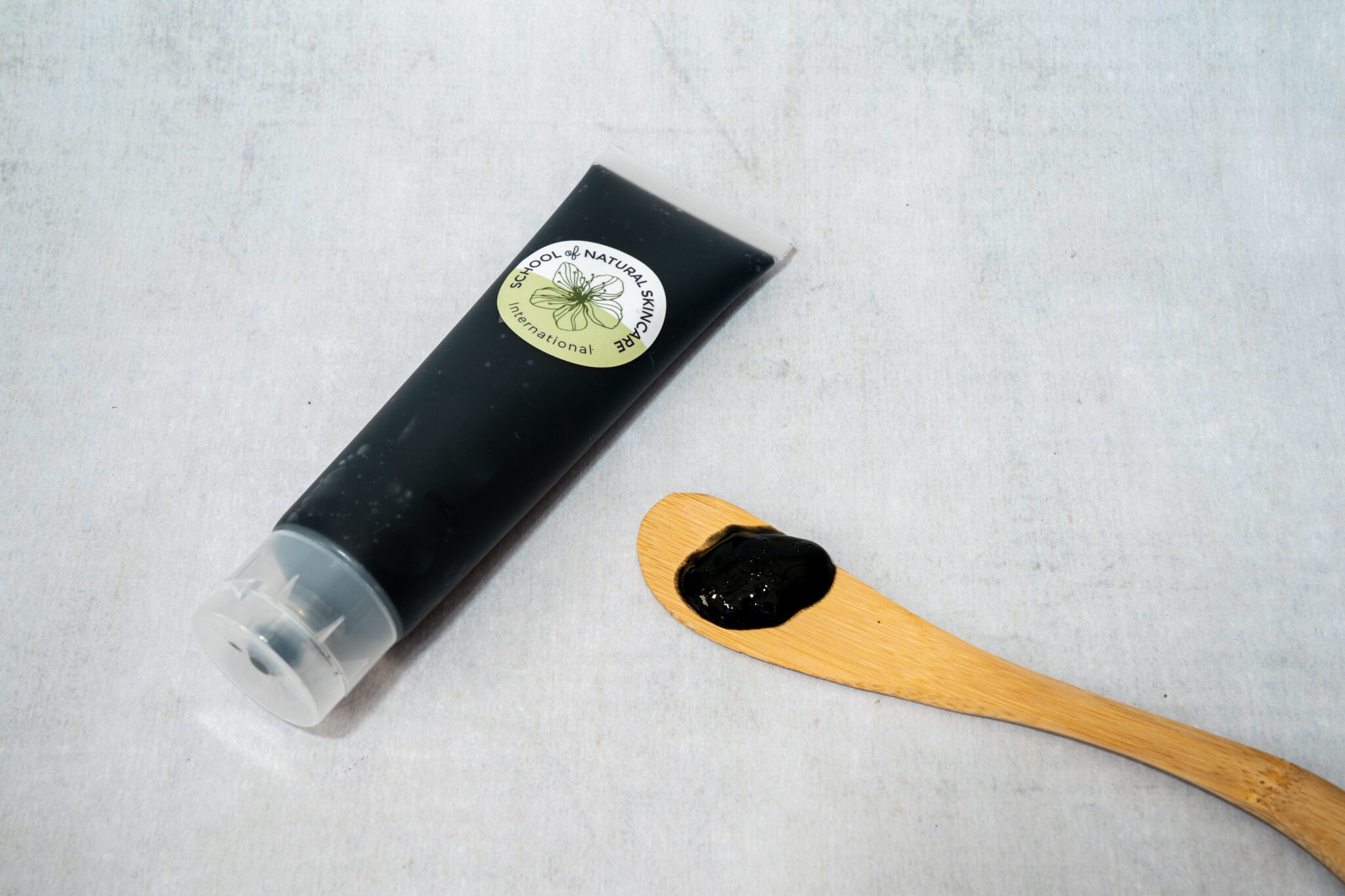 Natural skincare tube and wooden spatula with cream.