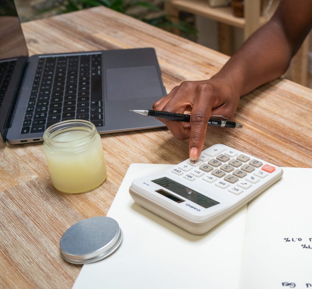 Calculating budget with laptop and calculator on desk.