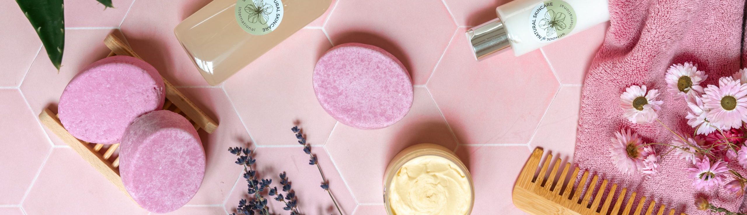 Pink skincare products with flowers on pink tiles