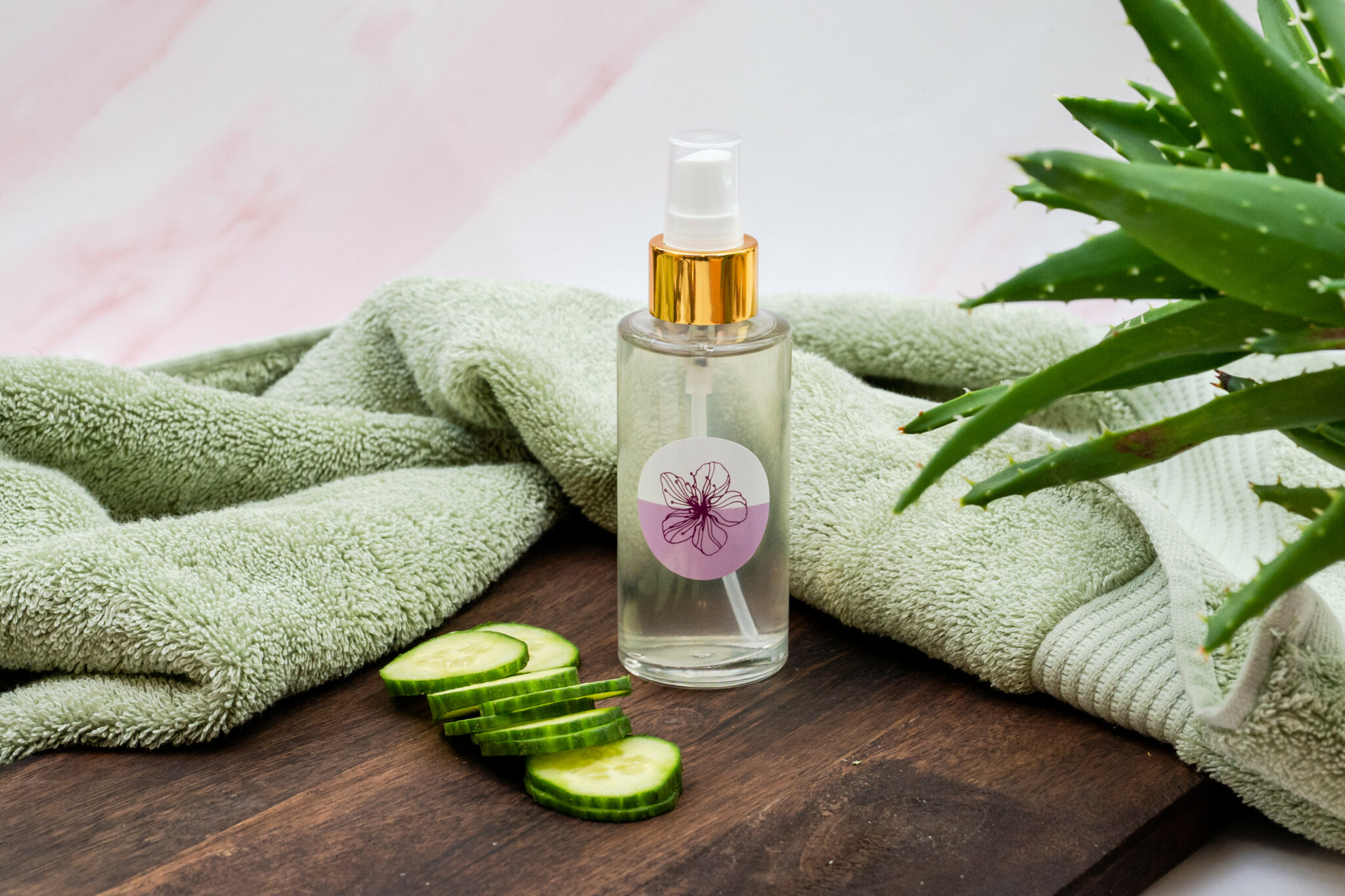 Aloe spray bottle with cucumber slices and towel.