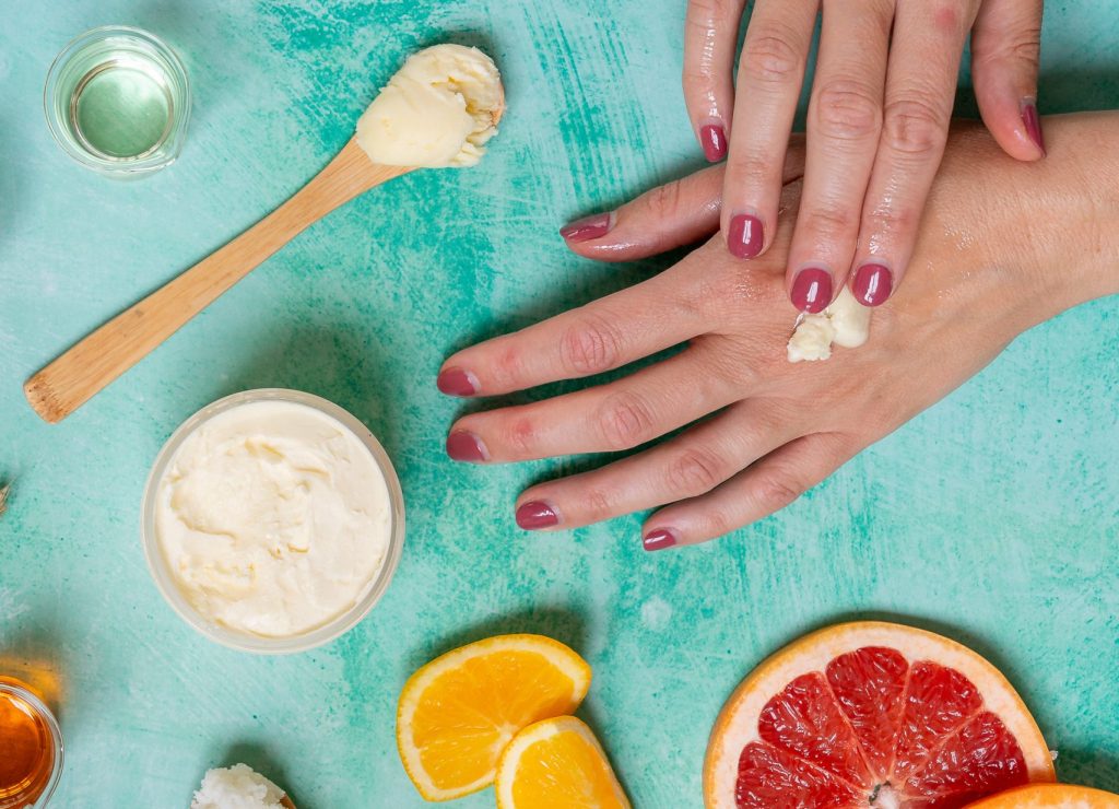 Applying hand cream with fruits on table