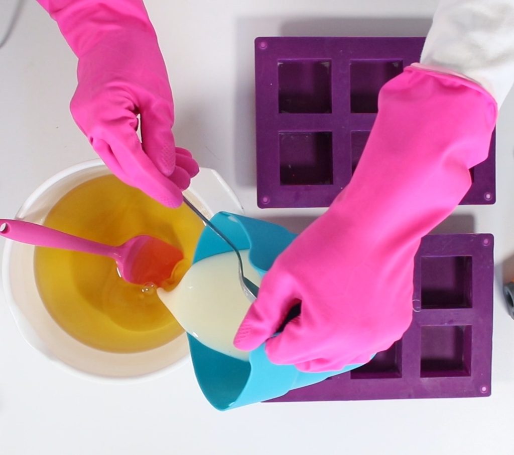 Making homemade soap with pink gloves and molds.