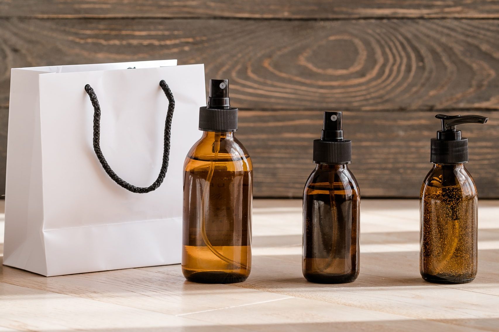 Brown spray bottles and white paper bag on table.