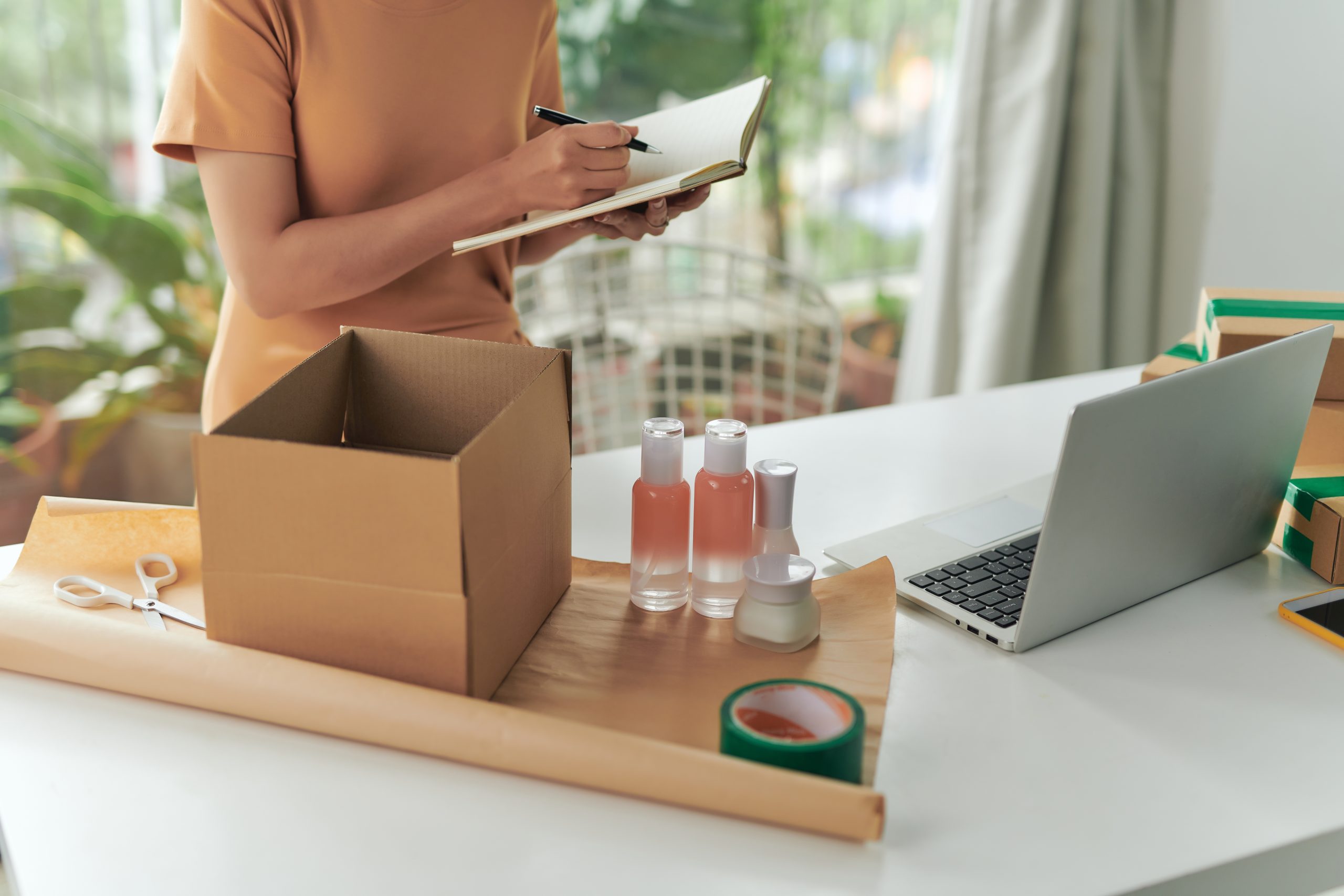 Packing skincare products with notes and laptop.