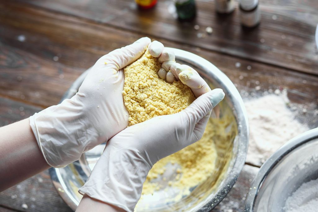 Hands preparing dough in mixing bowl.