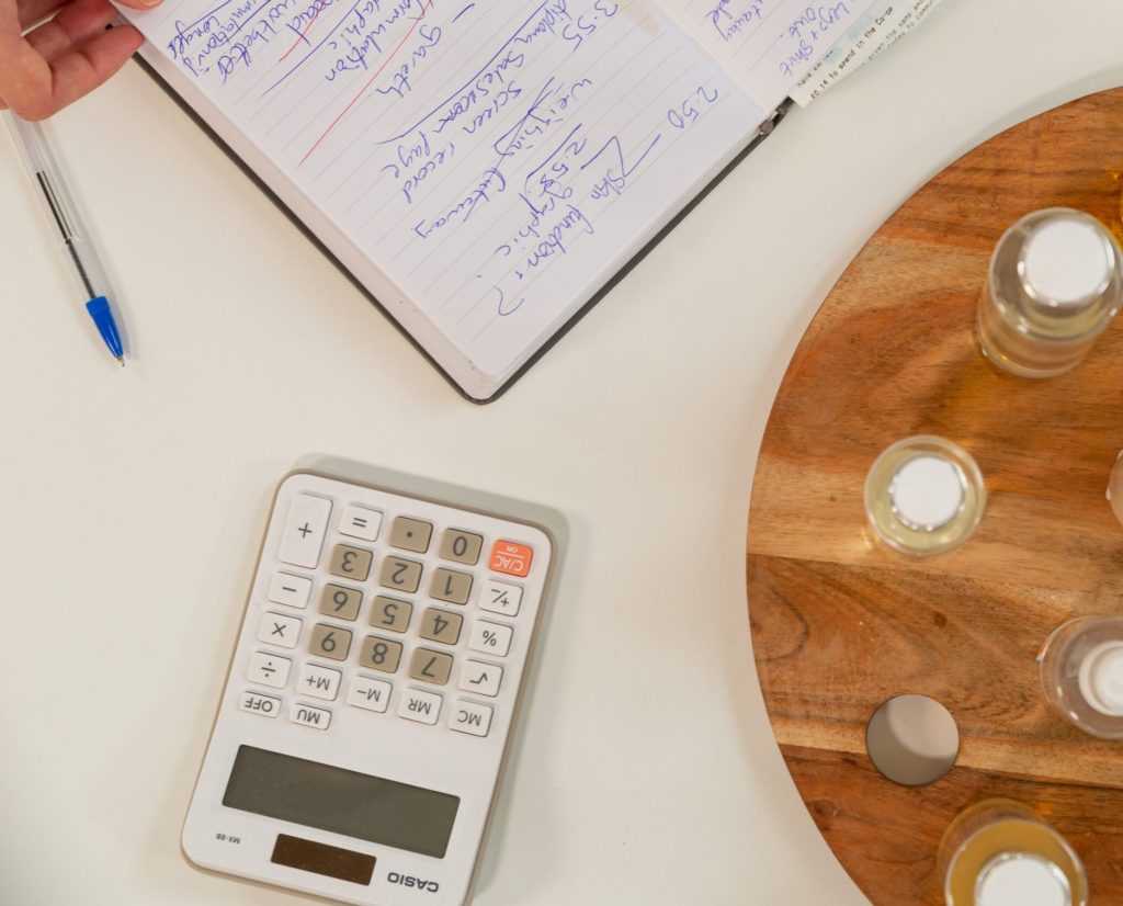 Notebook and calculator on table with glass bottles.