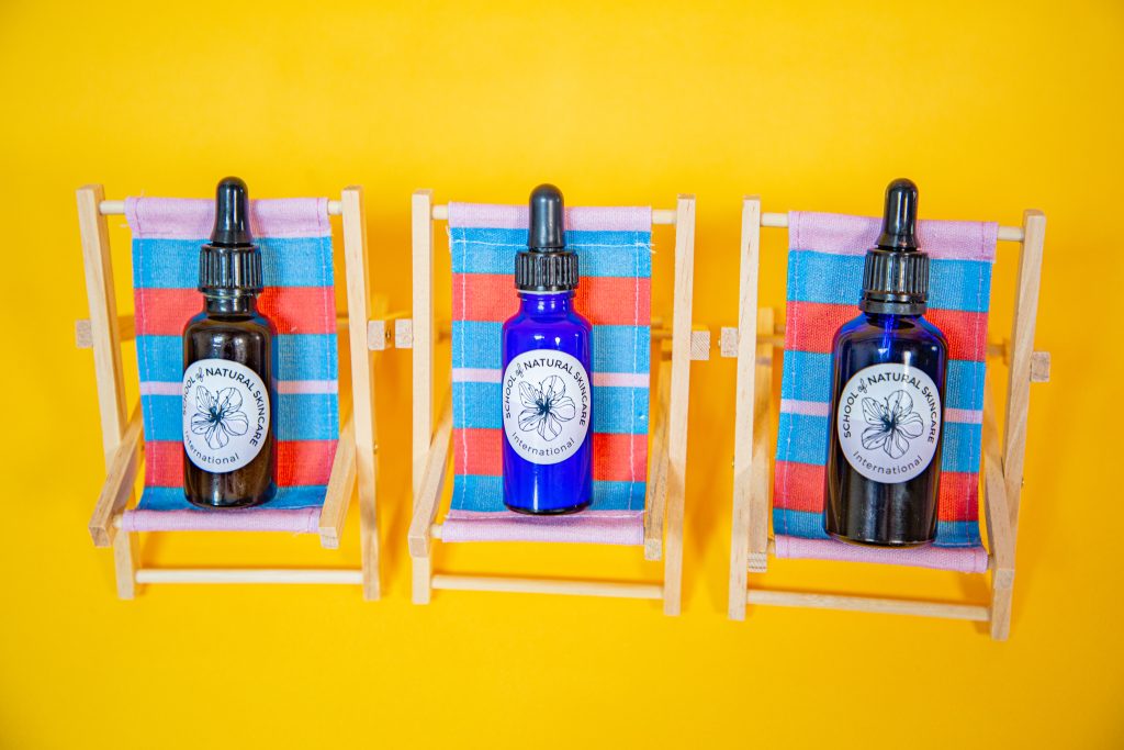 Natural skincare bottles on colorful chair seats.