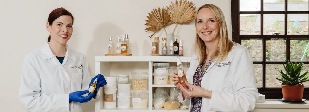 Two women showcasing natural skincare products.